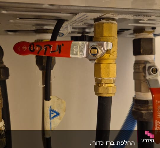 ברזי פליז עם ידיות אדומות וצינורות מחוברים
